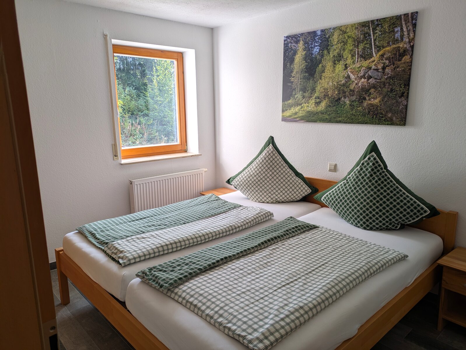 Geräumiges Schlafzimmer mit großem Doppelbett und Schwarzwald-Landschaftsbild in der Naturzeit Ferienwohnung
